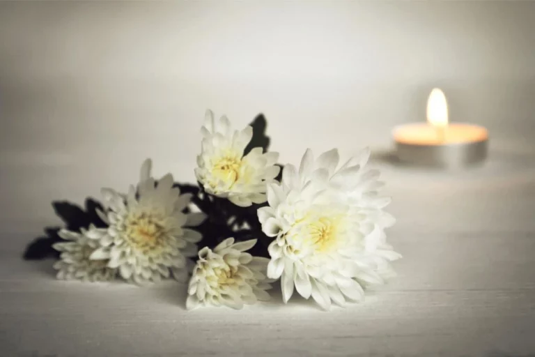 white flowers and a candle on white marble background