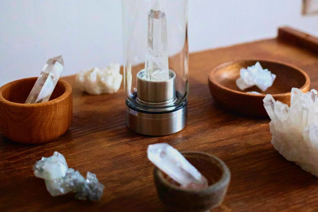 water bottle in the middle with a crystal inside and surrounded by coaster with a crystal