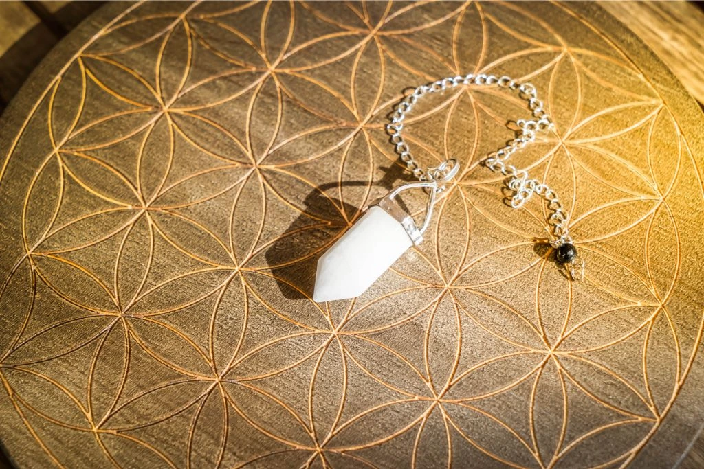 white crystal pendulum on a wooden background