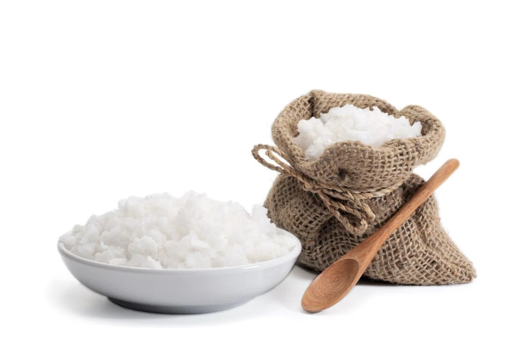 sea salt in a white bowl and jute bag with wooden spoon
