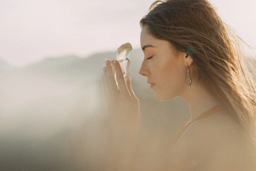 woman holding up a crystal in a foggy atmosphere