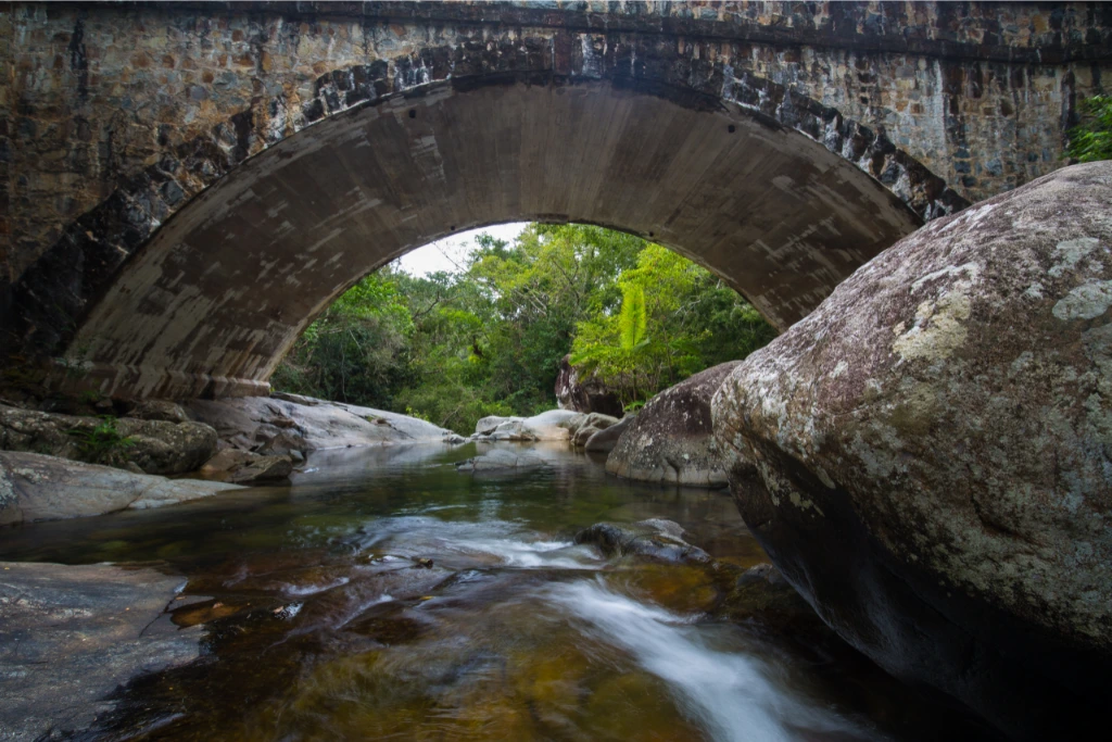 a creek with a stone bridge above it