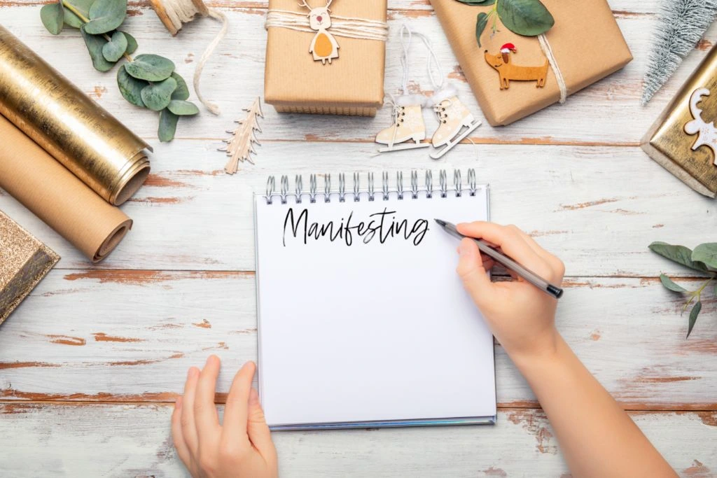 hand model writing the word manifesting on a piece of paper