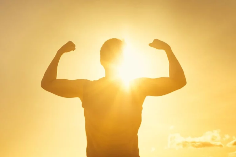 man flexing his muscle while facing towards the sun