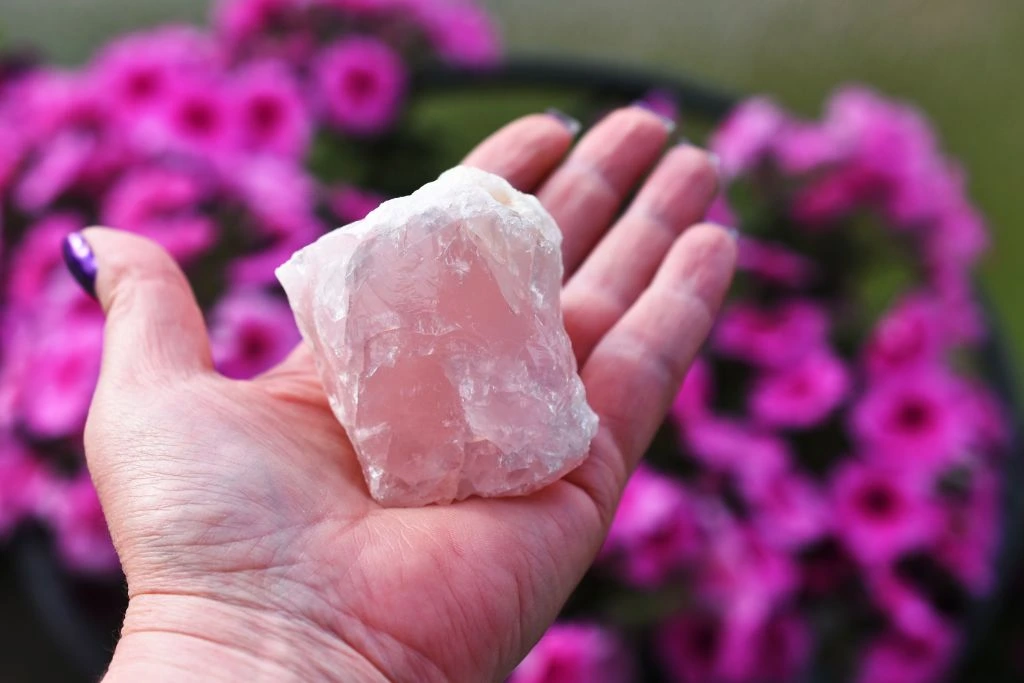 rose quartz on model's left hand with pink flower background