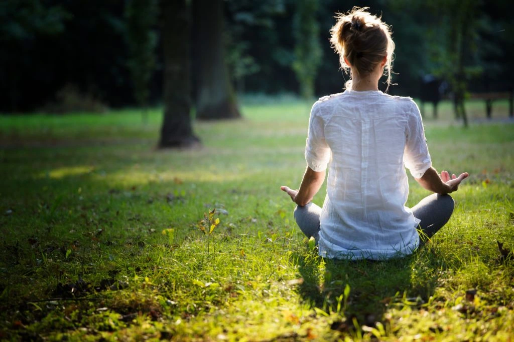 woman doing meditation outdoor while facing towards the sun