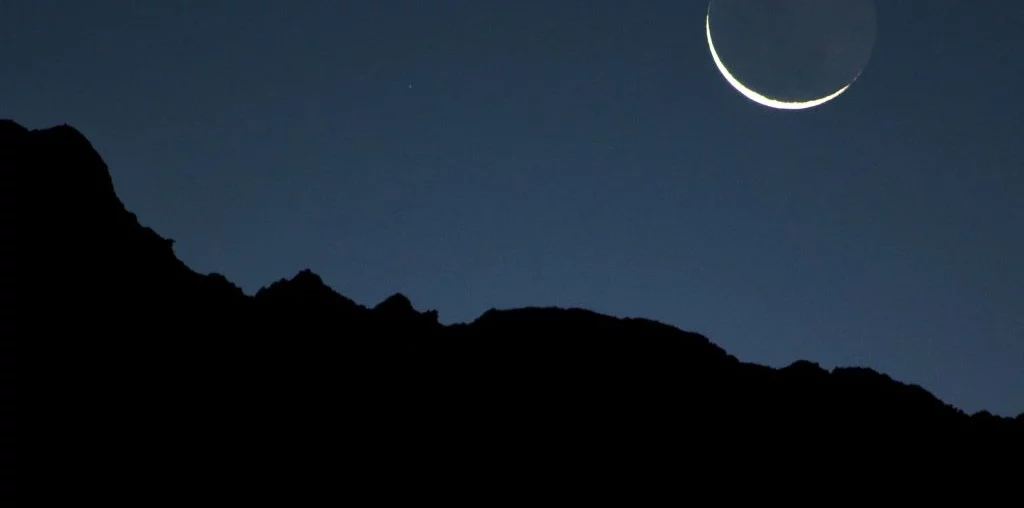 new moon on a dark mountain background