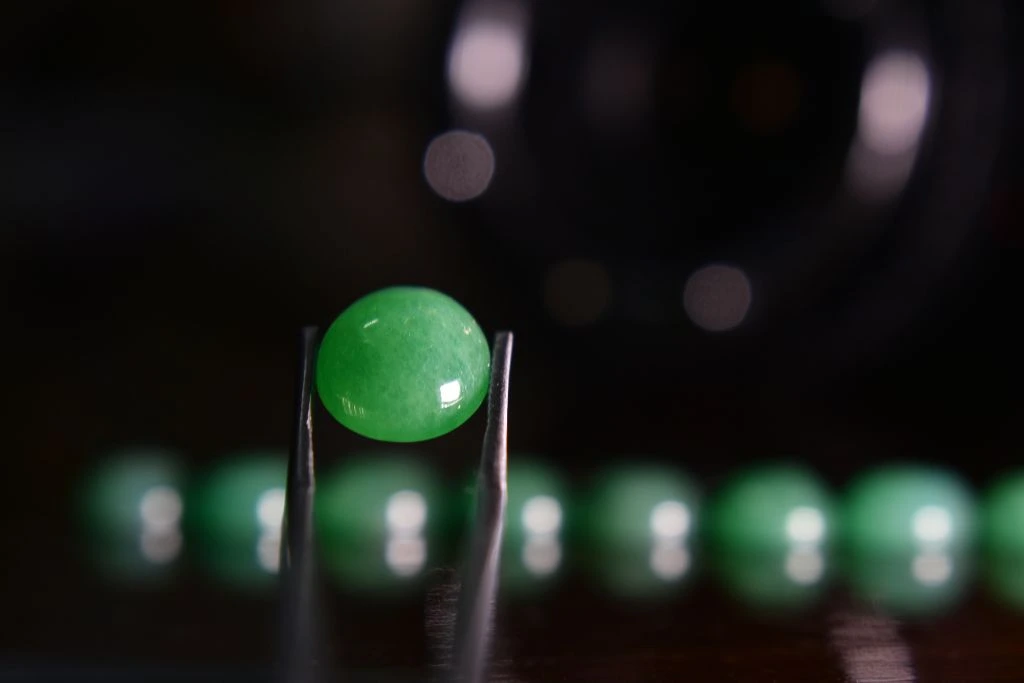 jade gemstone held up by pliers