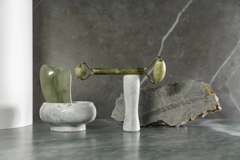 jade roller and gua sha on marble background