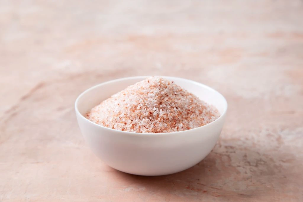 a bowl of pink himalayan salt on a pink background