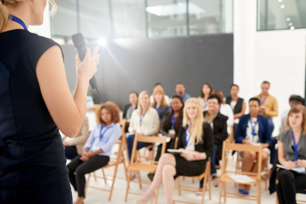 woman speaking in front of audiences