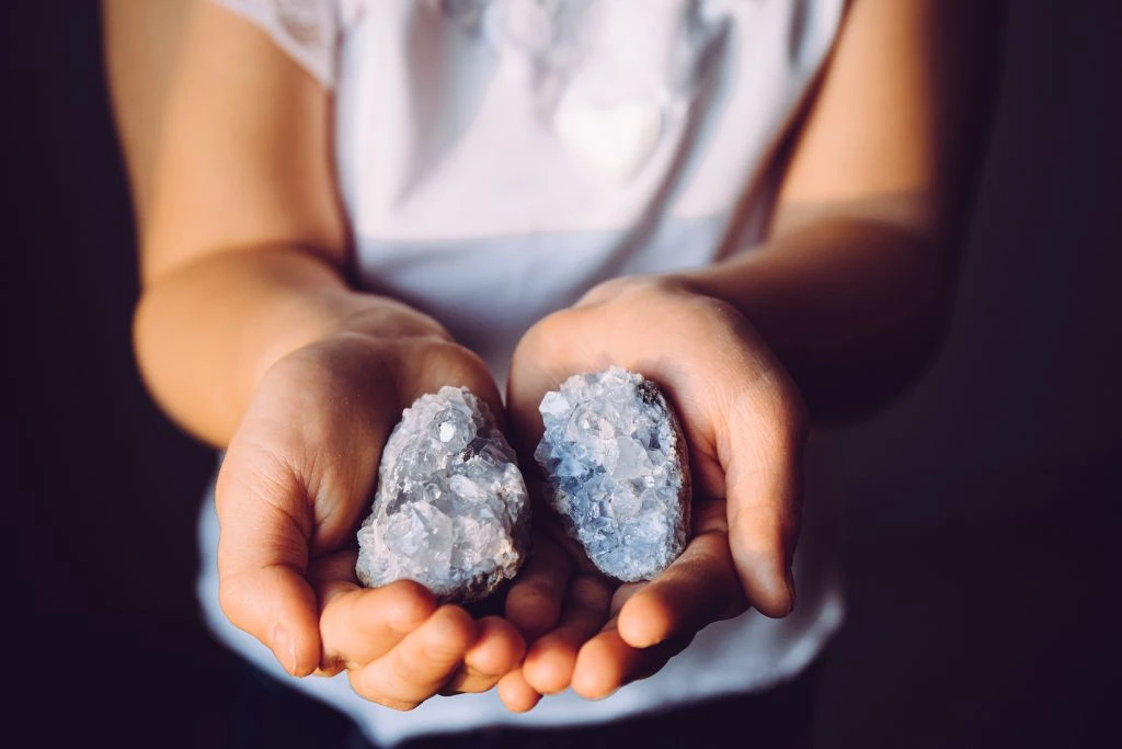 a woman holding celestite on the palm of her hands