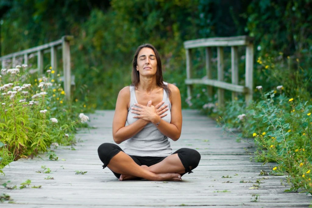 A woman sitting on a wooden pathway in nature