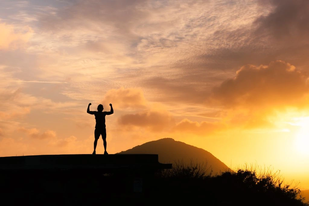 A person flexing his or her muscles during the sunset