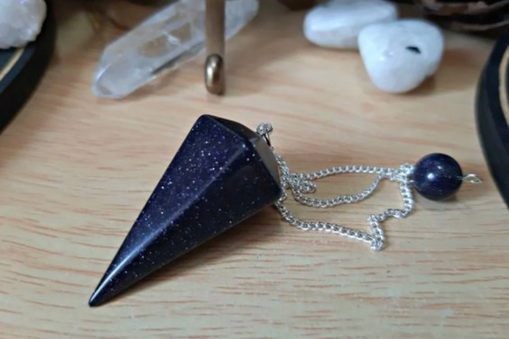 Blue Goldstone Pendulum on a table