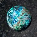 A polished Chrysocolla crystal on a black granite