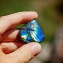 a man holding a labradorite crystal on an outdoor setting
