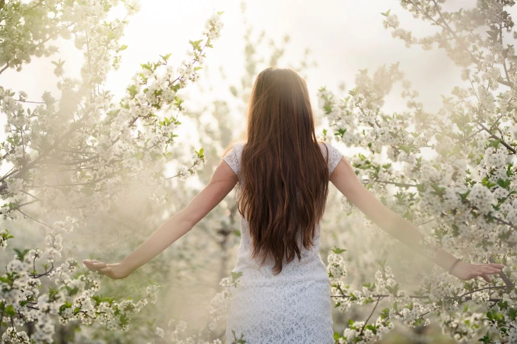 A woman standing and stretching her arms downward sideways in nature