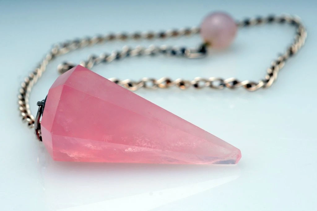 Rose Quartz pendulum on top of a glass surface