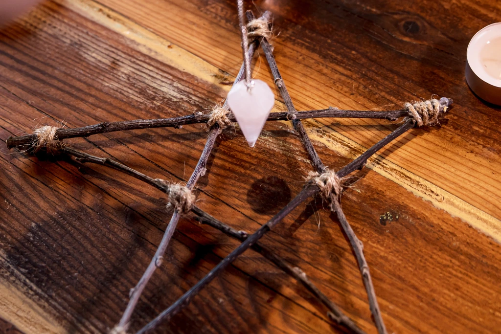 A selenite Pendulum hanging above a wooden star