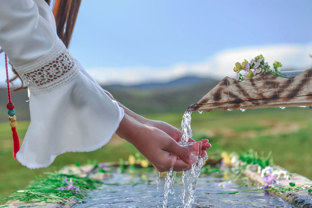 Woman cleansing her hand using water flowing through a bamboo stick