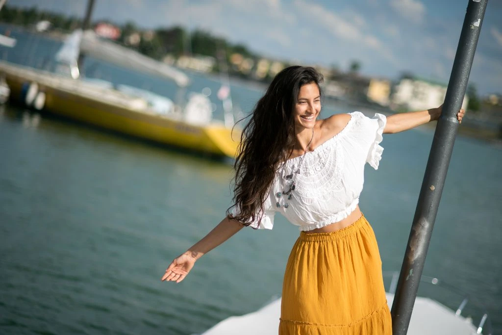 Woman wearing a yellow skirt and a white top, happily enjoying a boat ride 