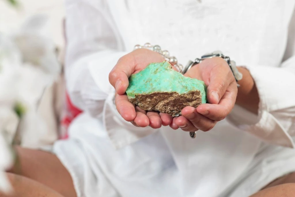 a woman holding a chrysoprase crystal on the palm of her hands
