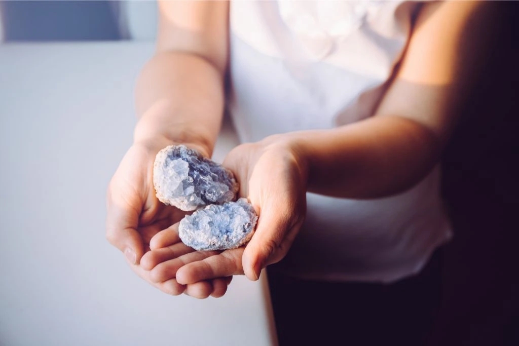 a woman holding celestite on the palm of her hands