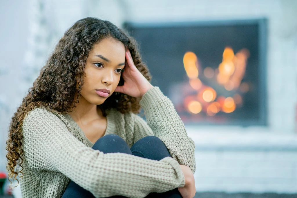 sad long curly- haired woman sitting on an outside location