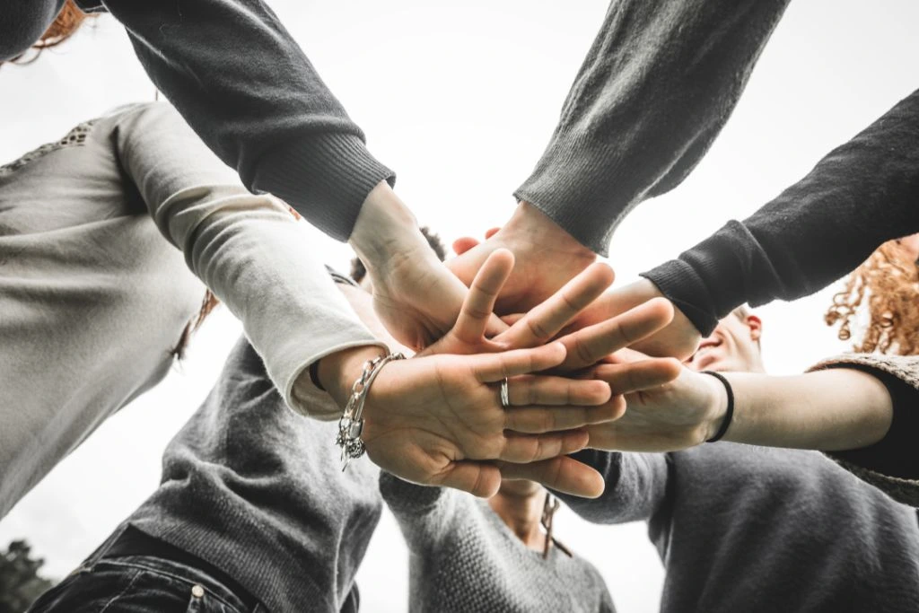 A group of people, putting their hand on top of each other