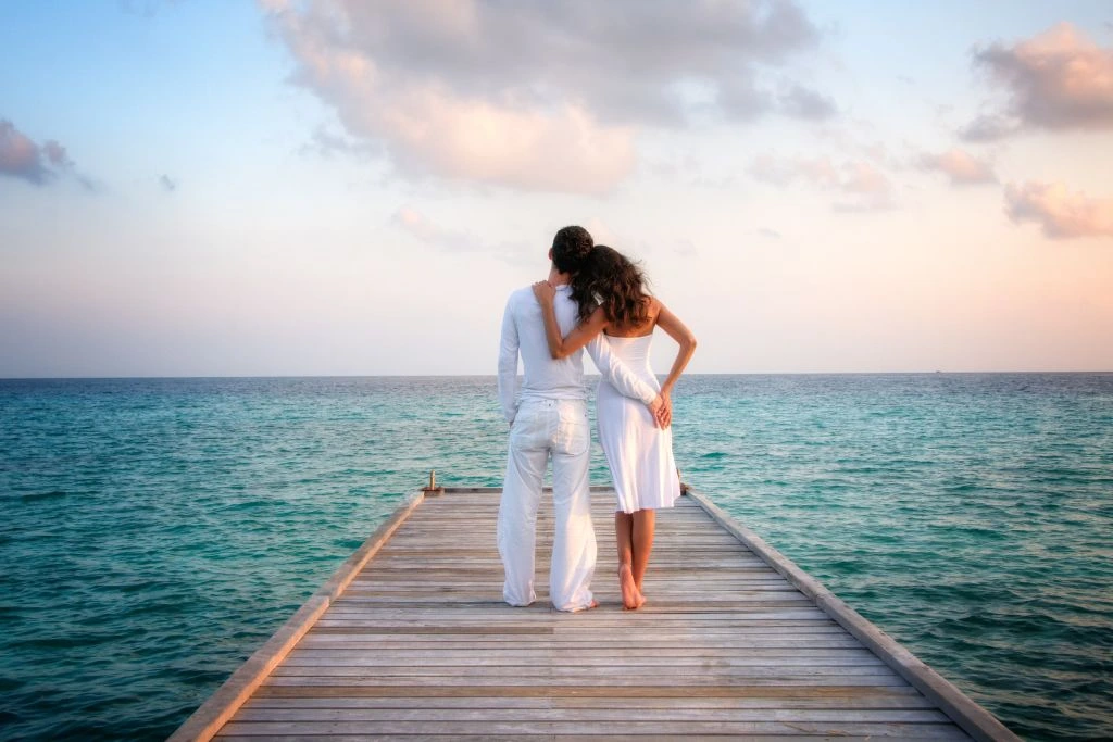 A couple wearing white clothes on a dock