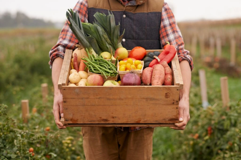 A man carrying different kinds of vegetable on the wooden tray