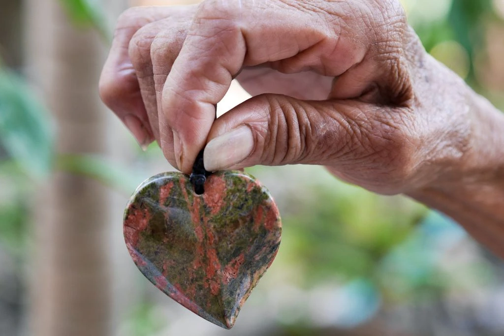 A person holding a heart shaped unakite