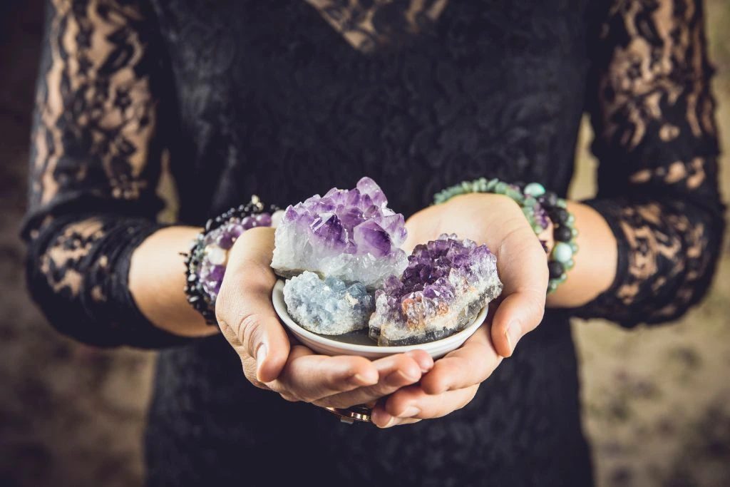 a woman holding on a saucer with different kinds of crystal cluster