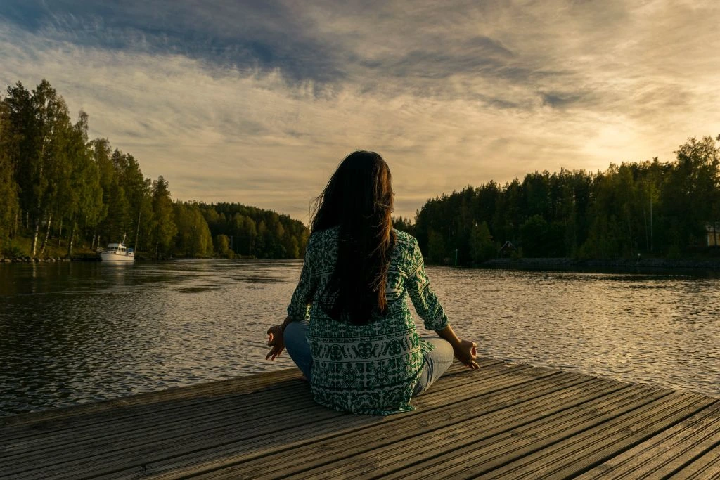 A woman meditating near the lake