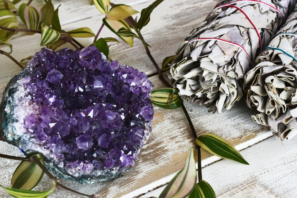 An amethysts crystal cluster and a smudge stick on the table