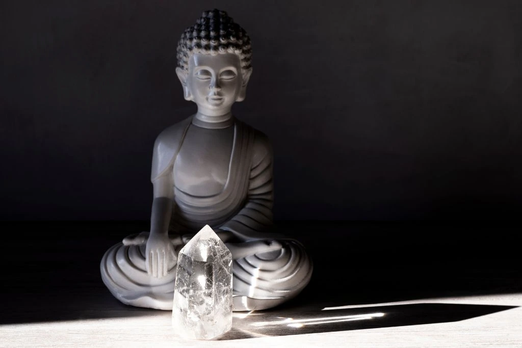 A buddha and clear quartz on the floor