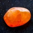 Polished Carnelian crystal placed on a black surface table