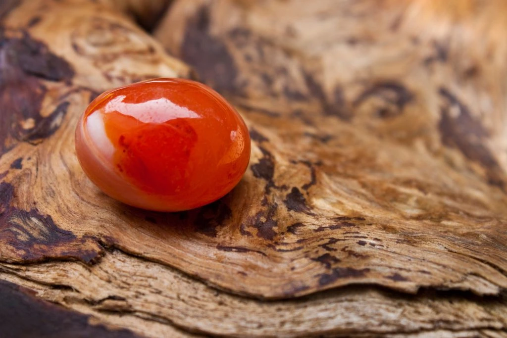 A polished carnelian crystal on a wood