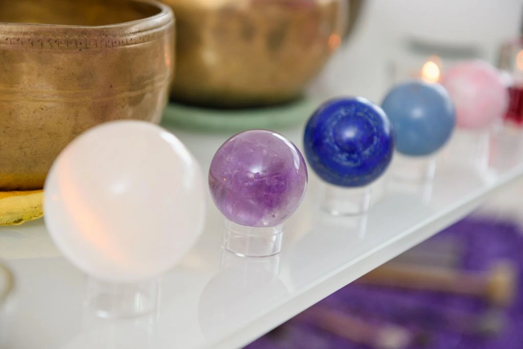 Singing bowls and Crystals spheres are displayed on a hanging shelf