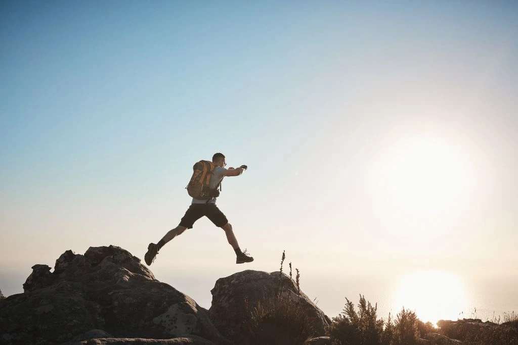 A man stepping from one rock to another