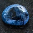 A polished Dumortierite crystal on a black granite