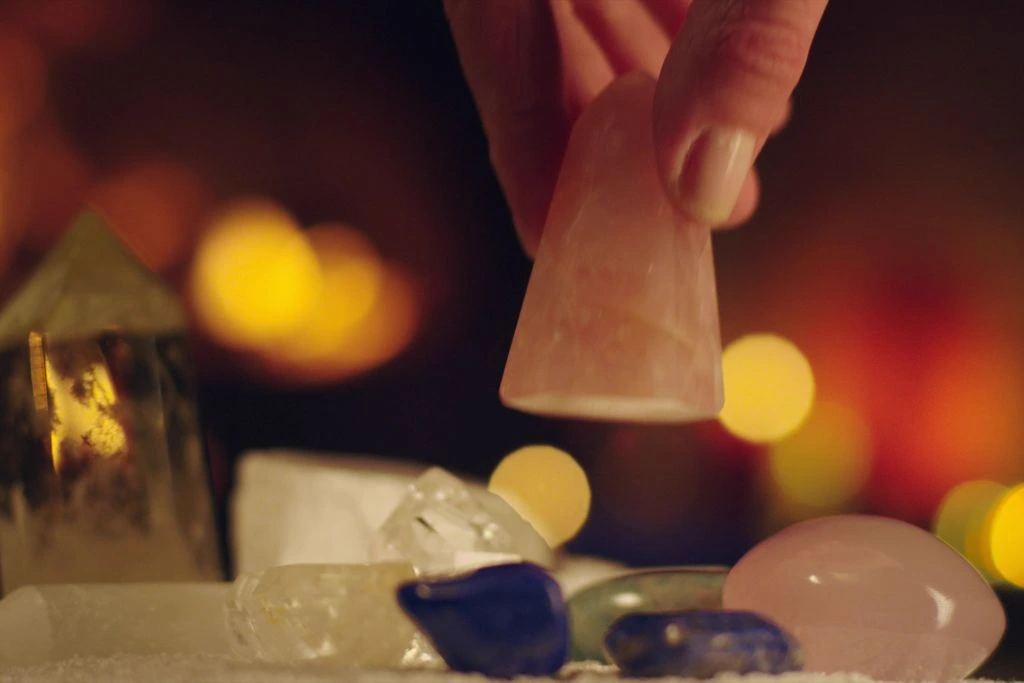 A person is getting a piece of crystal on the table full of crystals