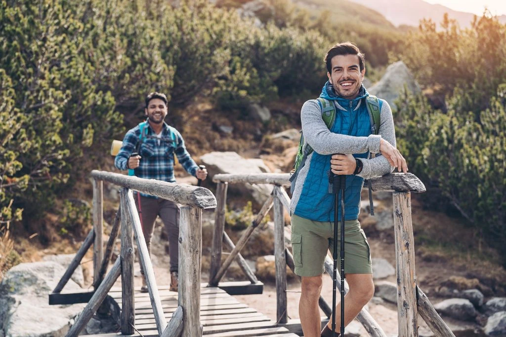 Two men standing near a wooden bridge in nature