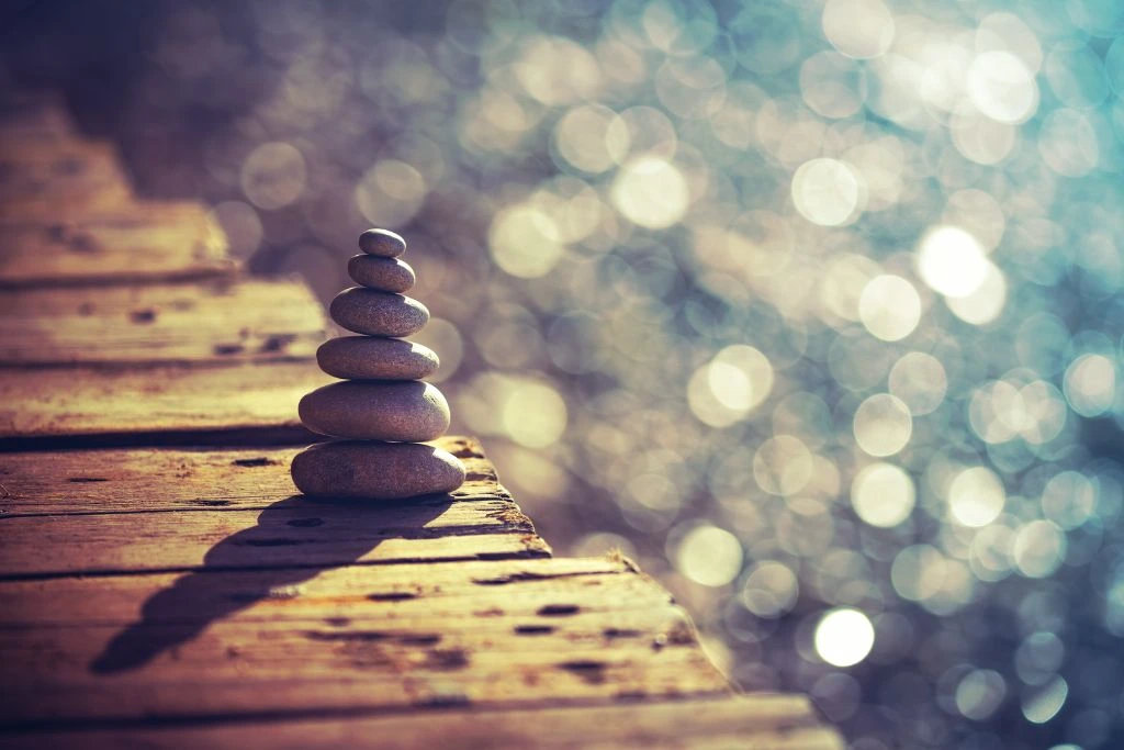 A stack of rocks that is balanced on a wooden plank