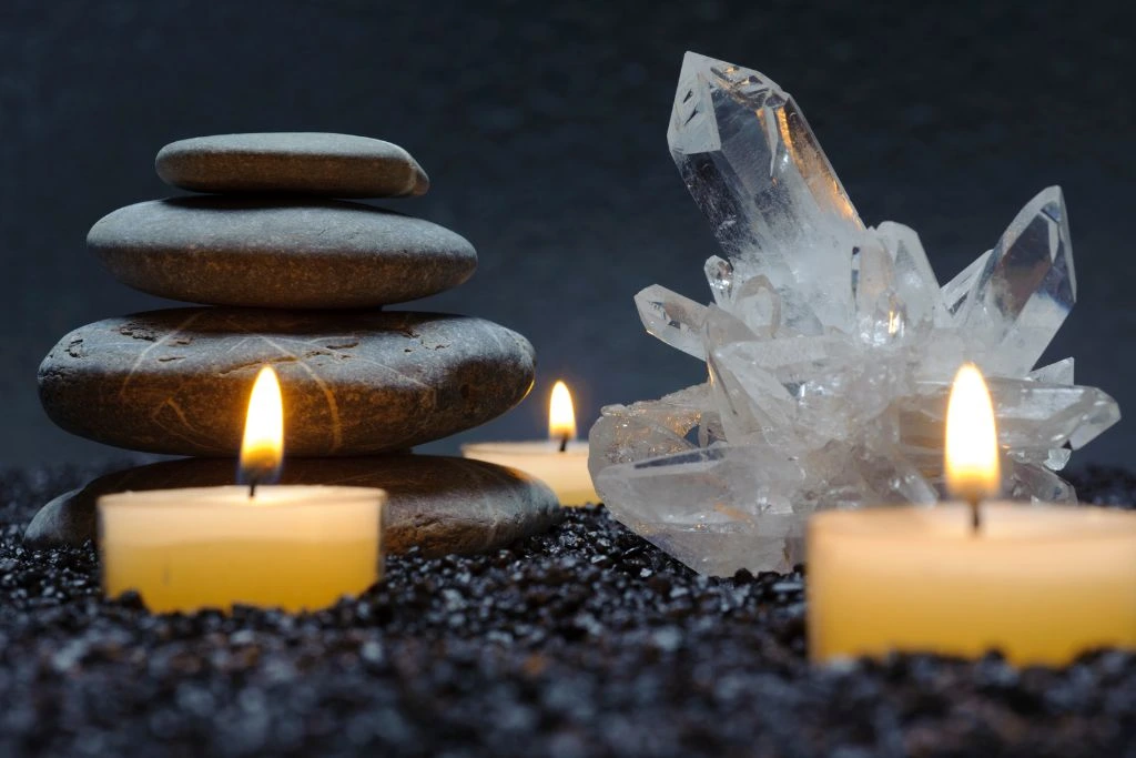 A Crystal with candles and rocks beside it.