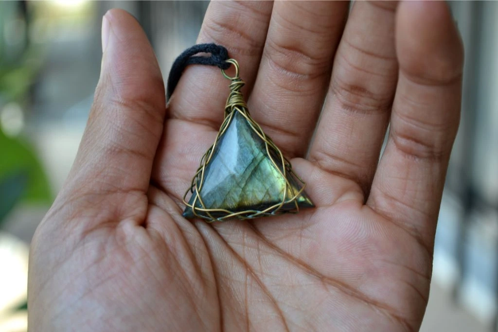 person holding a labradorite pendant