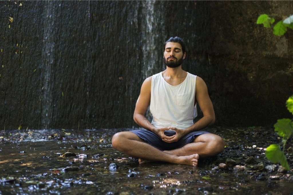 Man meditating nearby waterfalls