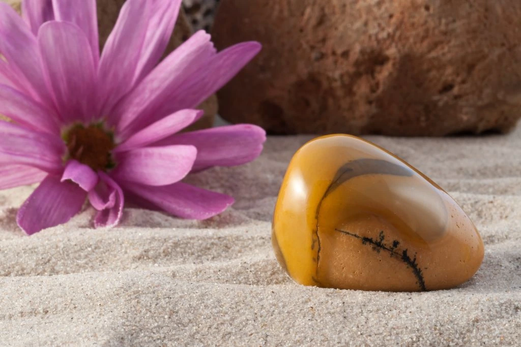 A polished mookaite crystal on the sand