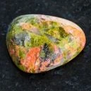 A polished unakite on a black granite